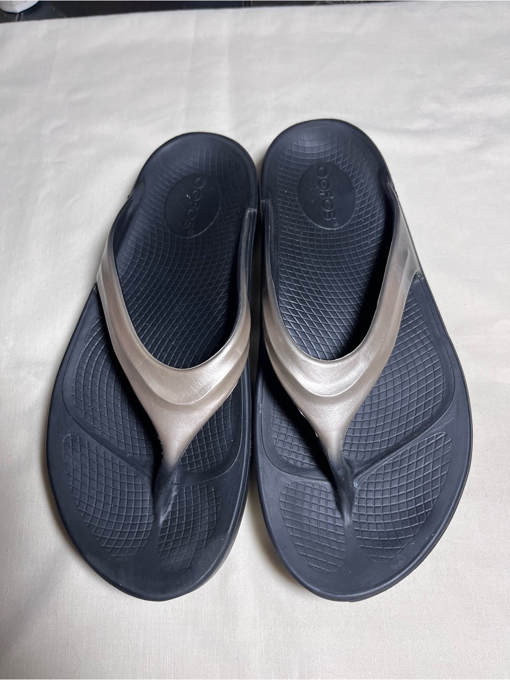 OOFOS Women’s Black Flip Flops with Metallic Taupe Straps